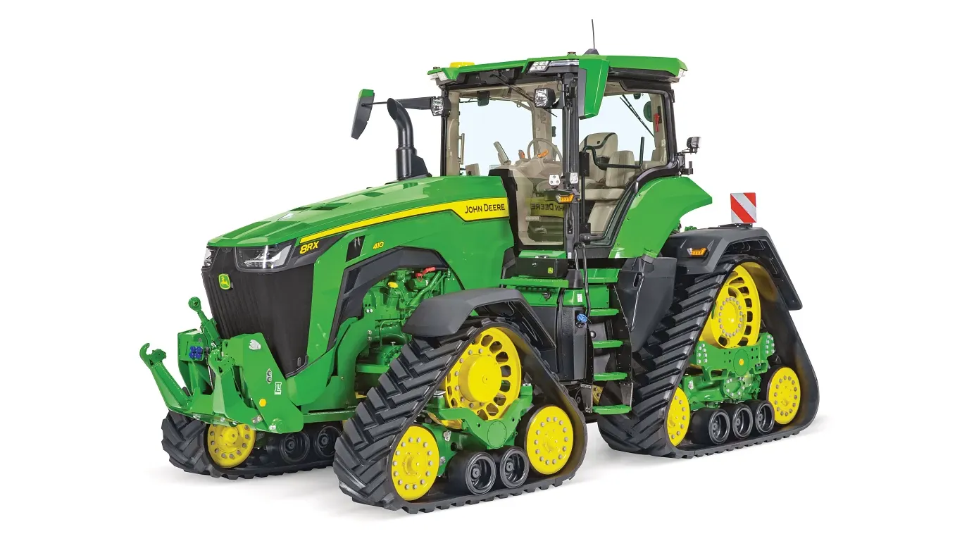 Τρακτέρ 8RX με τέσσερις ερπύστριες της John Deere, από μπροστά δεξιά γωνία σε λευκό φόντο, με ανεξάρτητες ερπύστριες και πλήρως κλειστή καμπίνα.