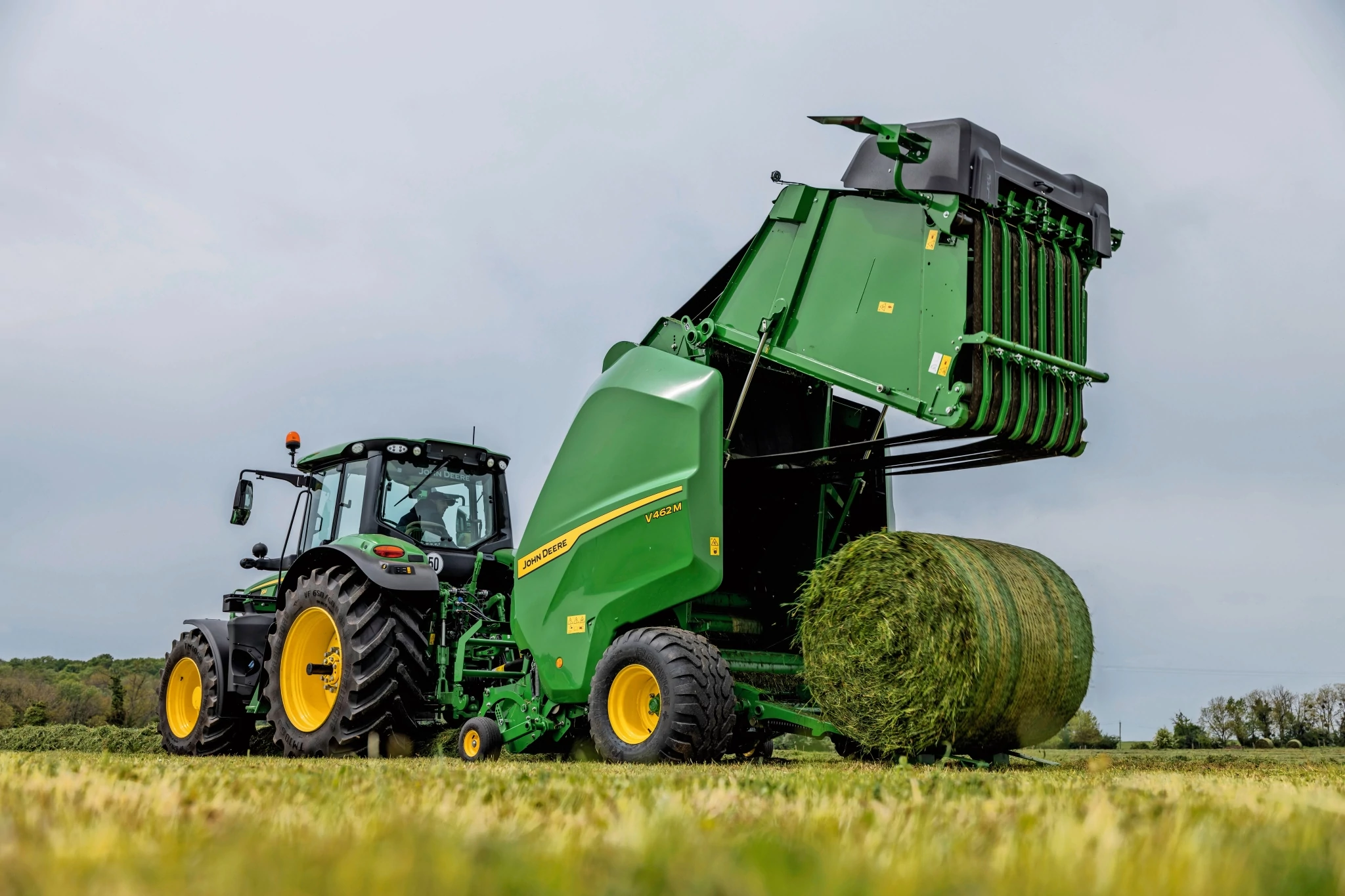 Χορτοδετικό John Deere V462M που ρυμουλκείται από ένα τρακτέρ 6M της John Deere για εξαγωγή δέματος χόρτου