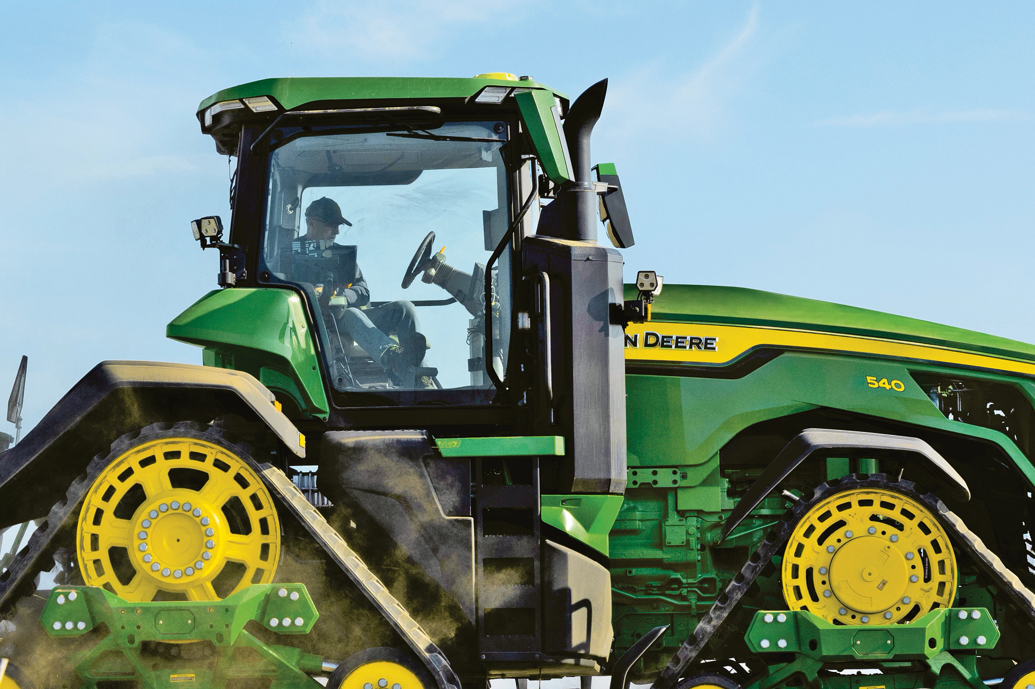 Κοντινό πλάνο δεξιάς πλευράς του τρακτέρ 8RX 540 με έναν αγρότη στην καμπίνα