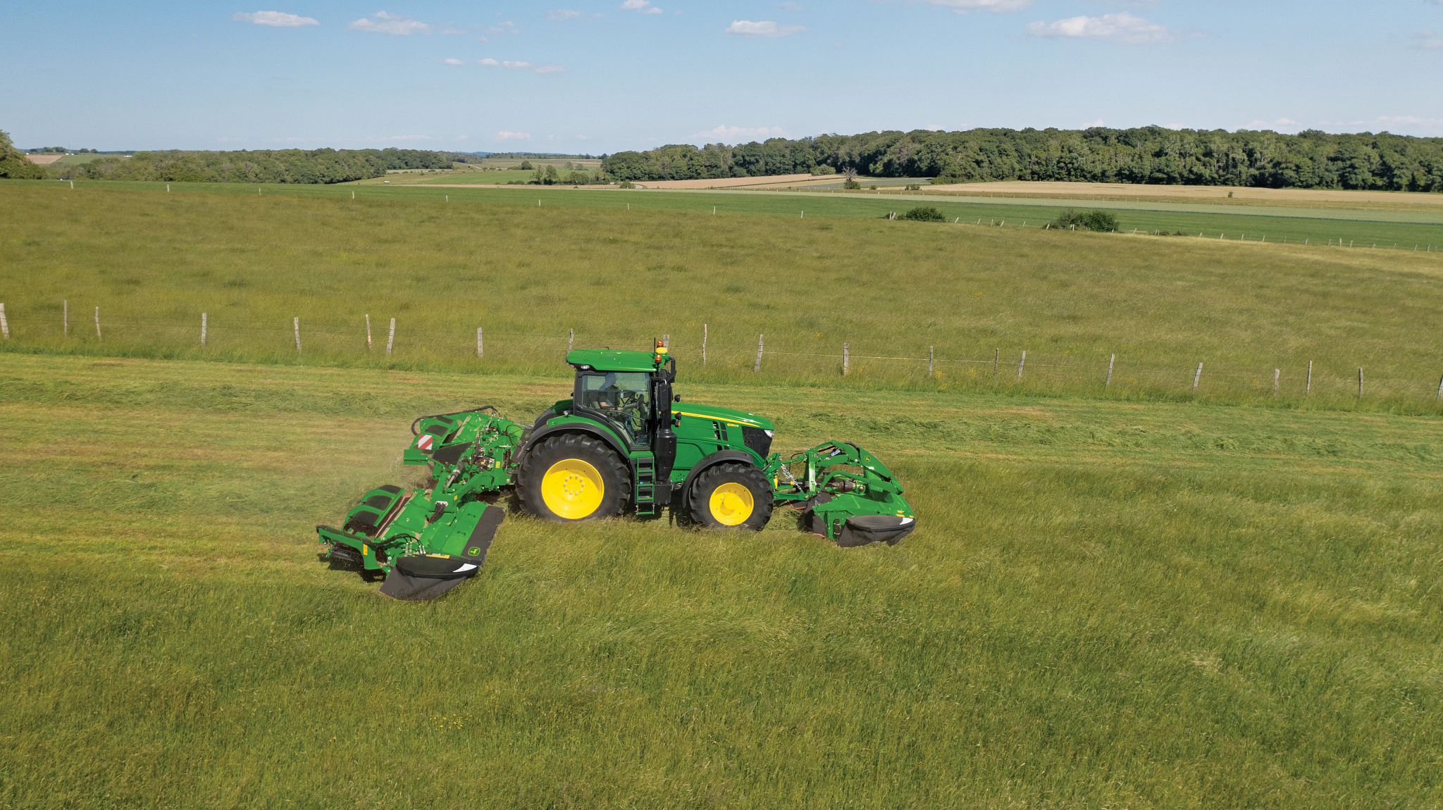 Όψη δεξιάς πλευράς ενός τρακτέρ που έλκει ένα διπλό πίσω τοποθετημένο χορτοκοπτικό-συνθλιπτικό με πτερωτή στον αγρό