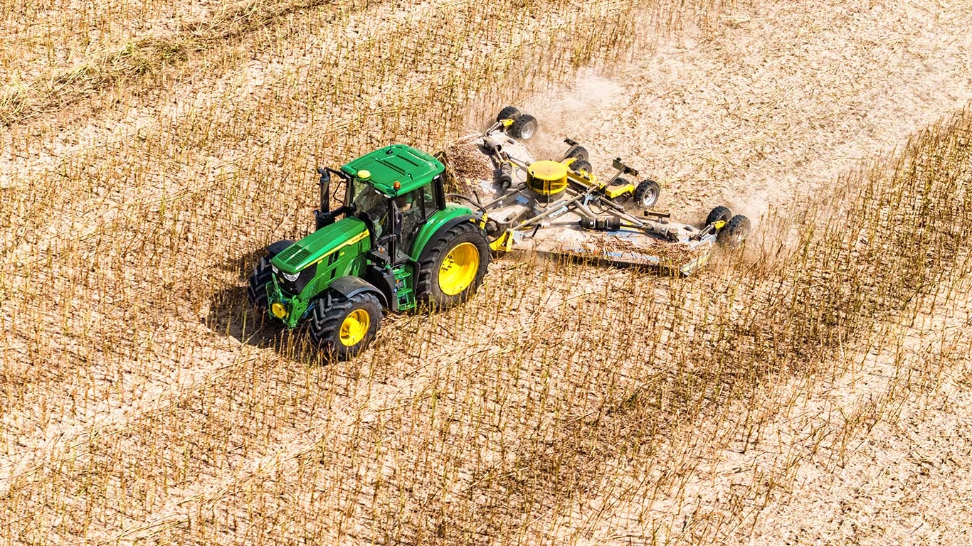 Ένα τρακτέρ εργάζεται ενεργά σε έναν αγρό, επισημαίνοντας τον ουσιαστικό ρόλο των μηχανημάτων στη σύγχρονη γεωργία.