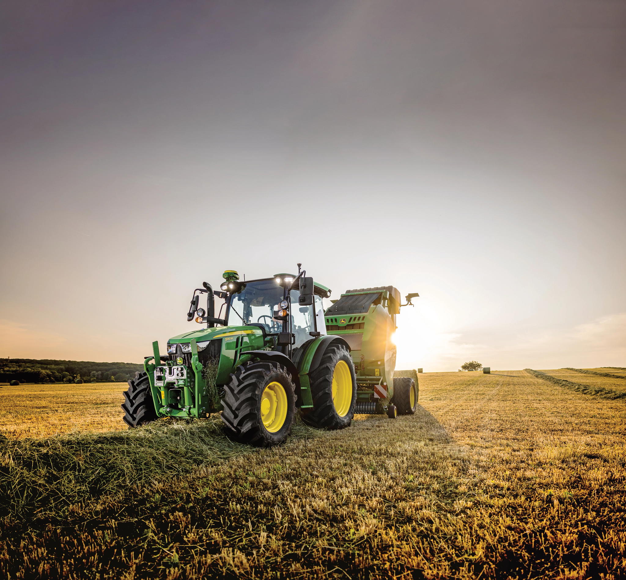 Μπροστινή αριστερή όψη ενός τρακτέρ της σειράς 5M που έλκει ένα χορτοδετικό στον αγρό