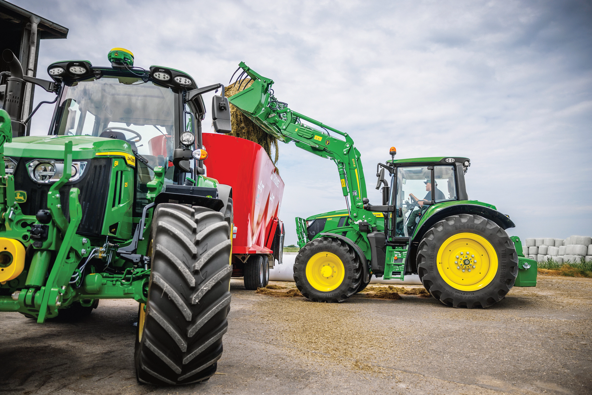 Ένα πράσινο τρακτέρ και ένα κόκκινο τρακτέρ σταθμευμένα δίπλα δίπλα σε ένα αγροτικό περιβάλλον, που αναδεικνύουν τα ζωντανά χρώματα πάνω στο τοπίο.