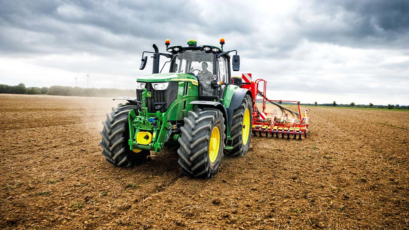 Ένα τρακτέρ φαίνεται να οργώνει έναν αγρό, περιστρέφοντας το έδαφος για να προετοιμαστεί για γεωργικές δραστηριότητες φύτευσης.