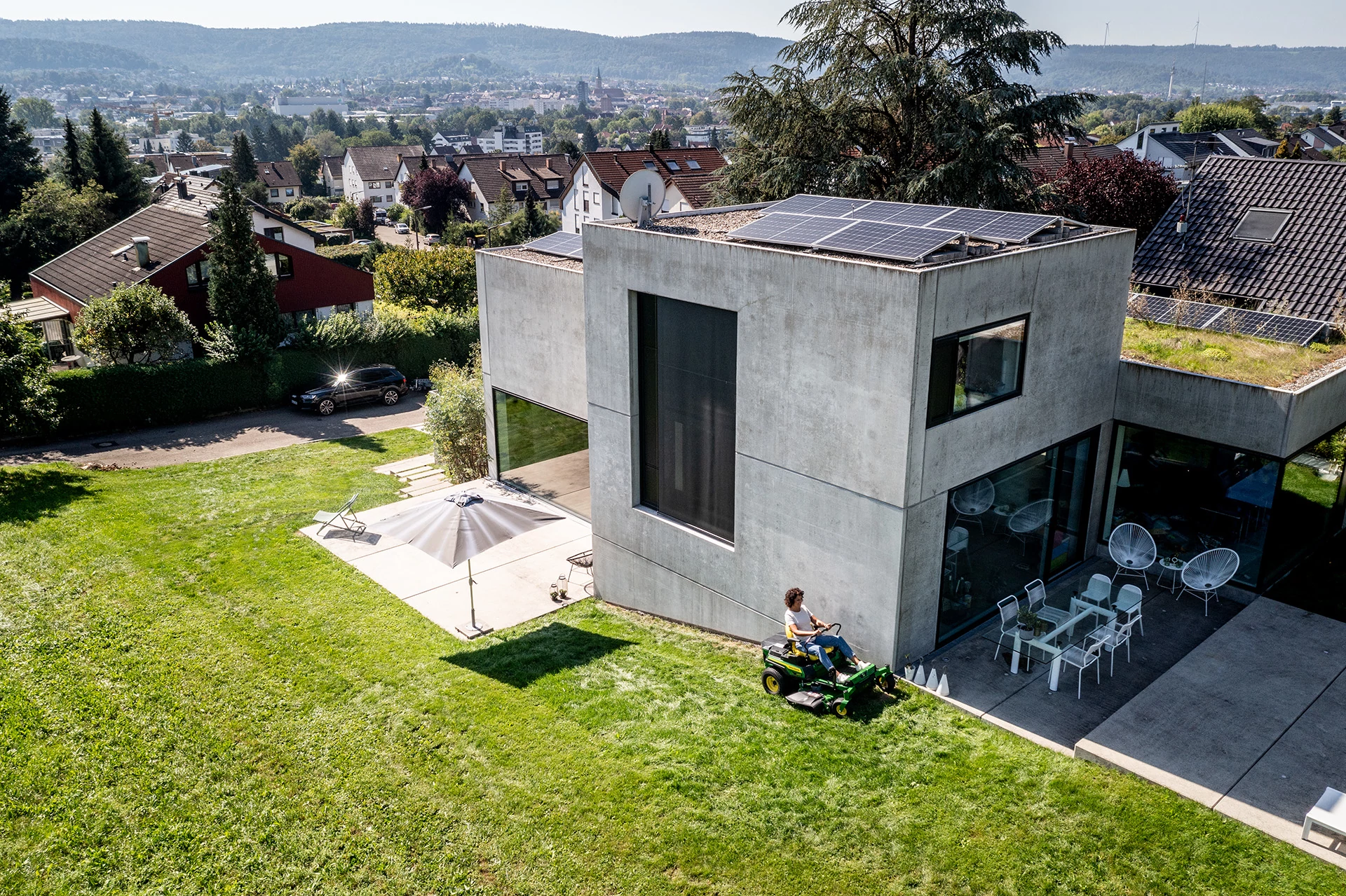 Η γυναίκα οδηγεί το οικιακό χορτοκοπτικό Z370r στο γκαζόν μιας κατοικίας σε πλαγιές