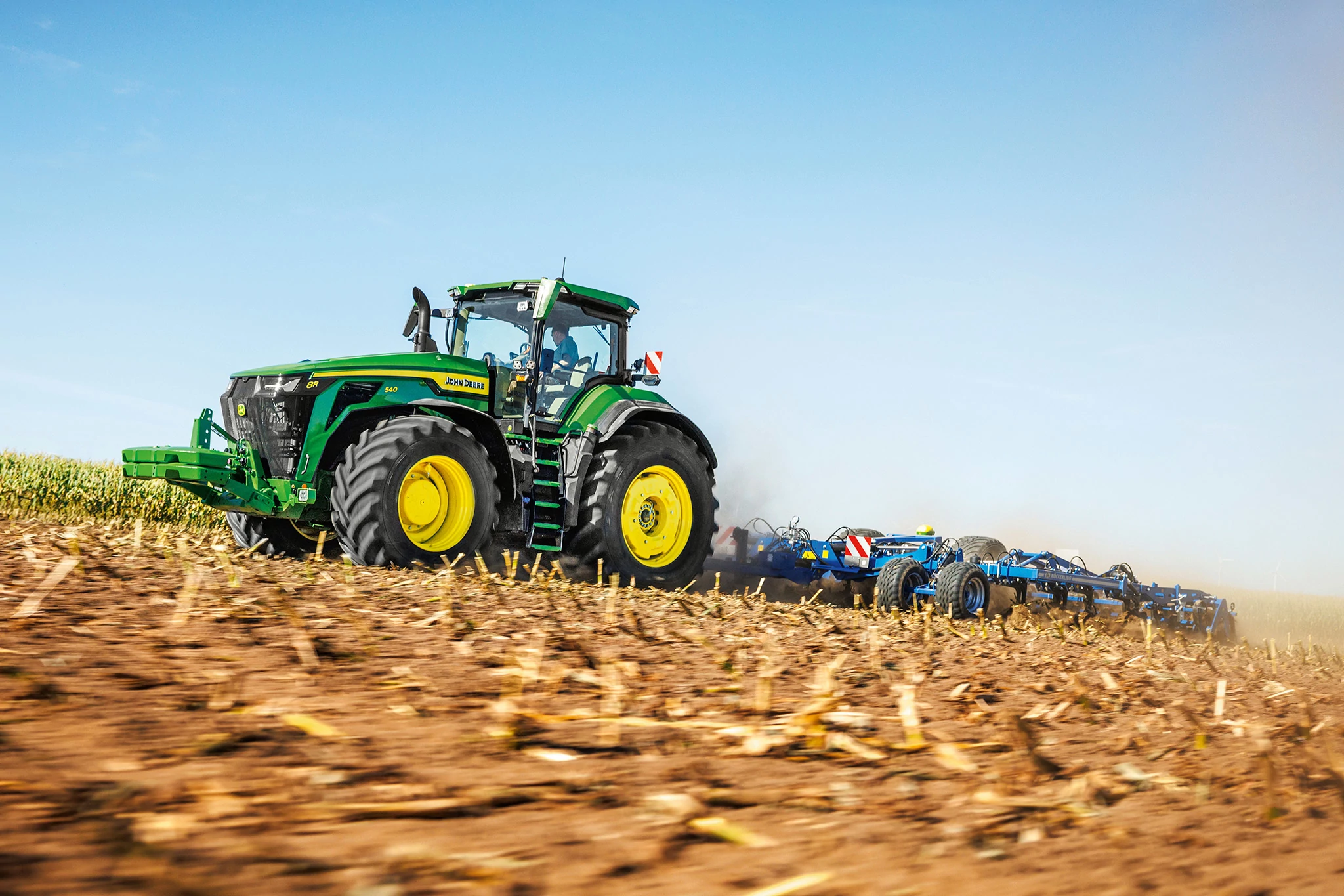 Τρακτέρ 8R 540 που τραβάει ένα εργαλείο οργώματος σε χωράφι με κομμένο καλαμπόκι