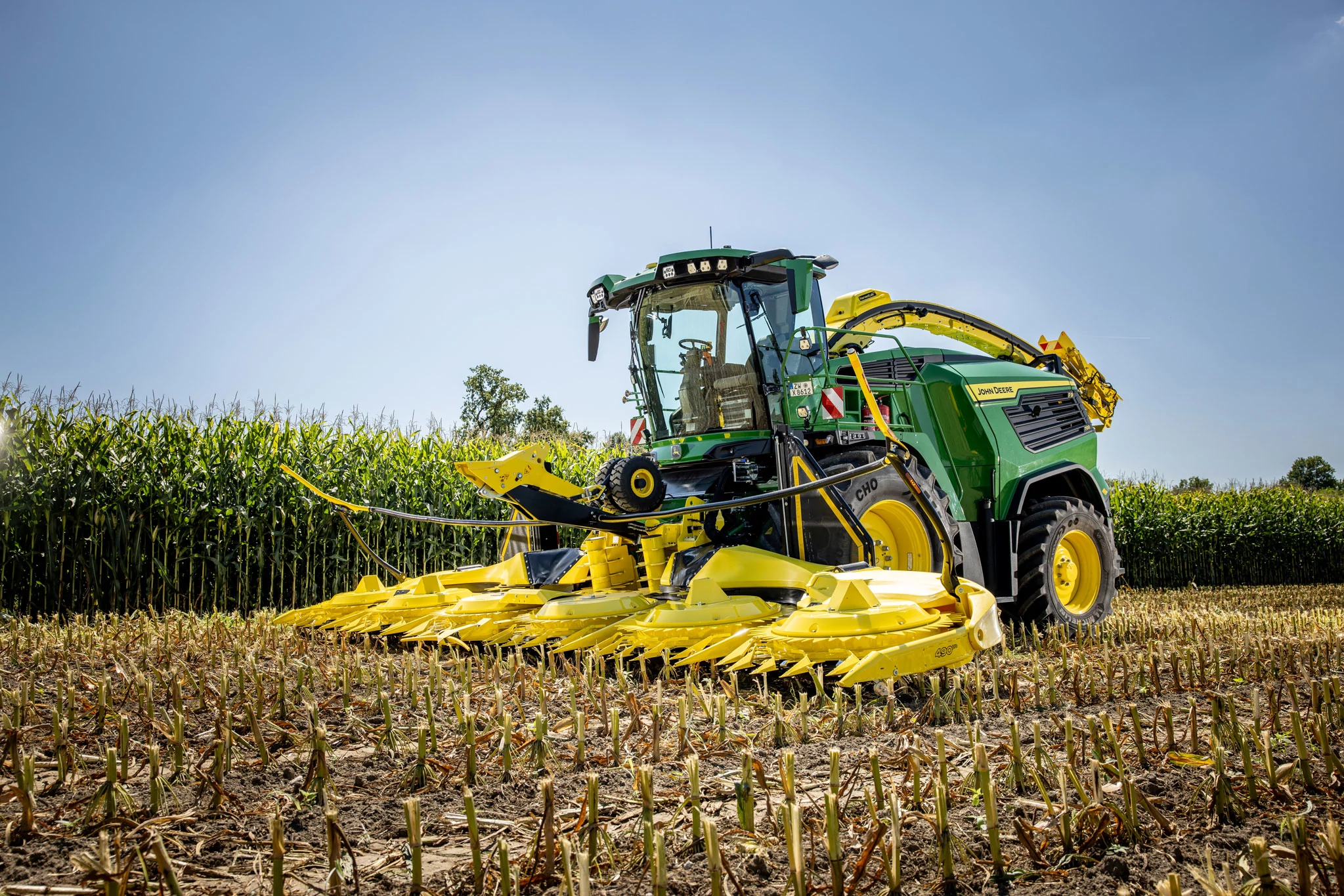 Μπροστινή αριστερή όψη μιας περιστροφικής κεφαλής κοπής σοδειάς 490Pro σε αυτοκινούμενο ενσιρωκοπτικό μηχάνημα F9 700 σε χωράφι καλαμποκιού το σούρουπο