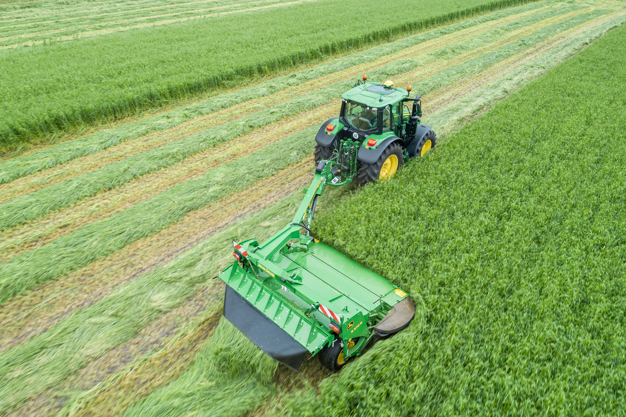 Το μπροστινό χορτοκοπτικό S310R της John Deere με φαρδιά μπάρα κοπής και προστατευτικές φούστες φαίνεται από μπροστά σε λευκό φόντο.