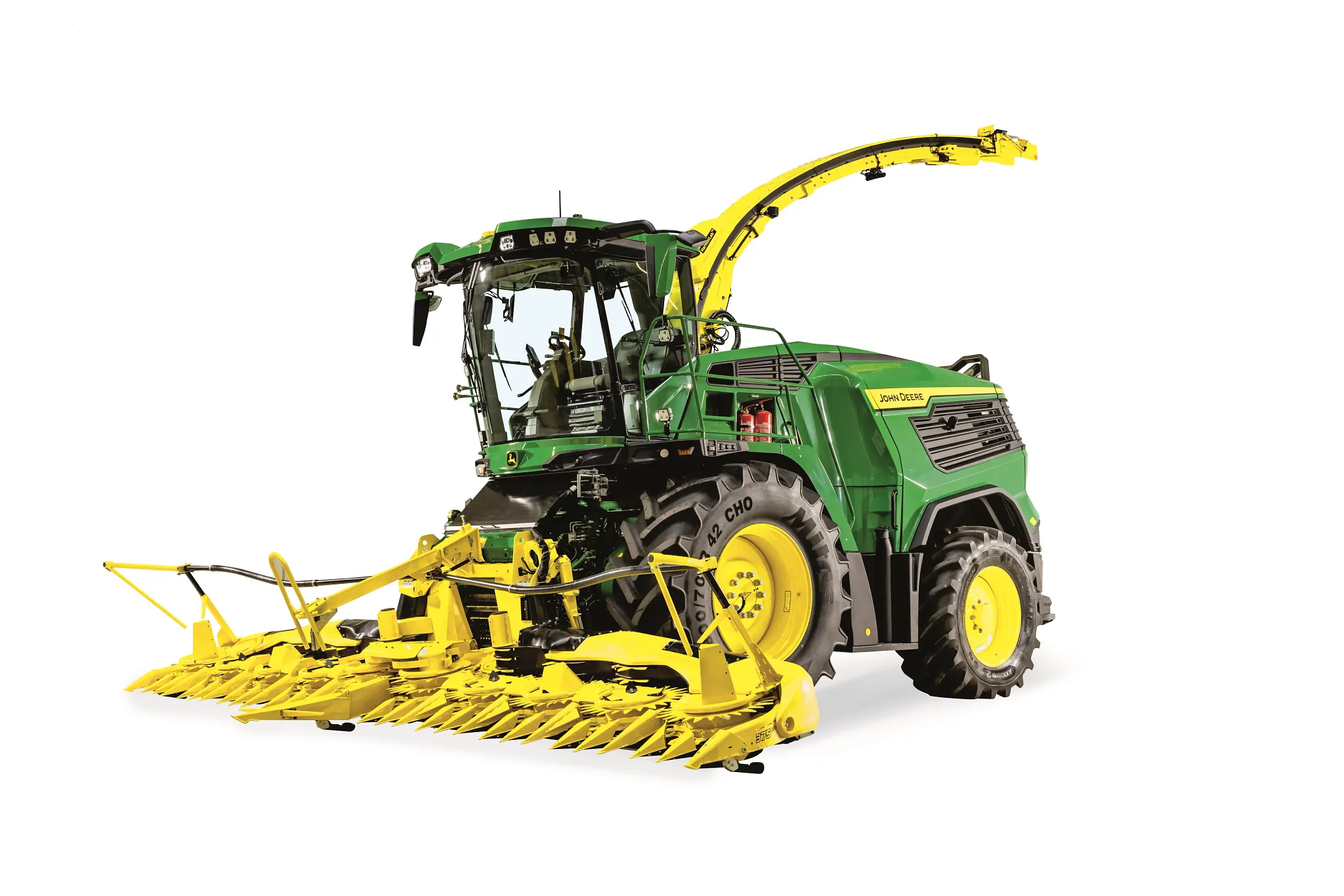 Αυτοκινούμενο ενσιρωκοπτικό μηχάνημα John Deere με μεγάλη κεφαλή κοπής καλαμποκιού και σωλήνα εκφόρτωσης σε απεικόνιση υπό γωνία, μπροστά και σε λευκό φόντο.